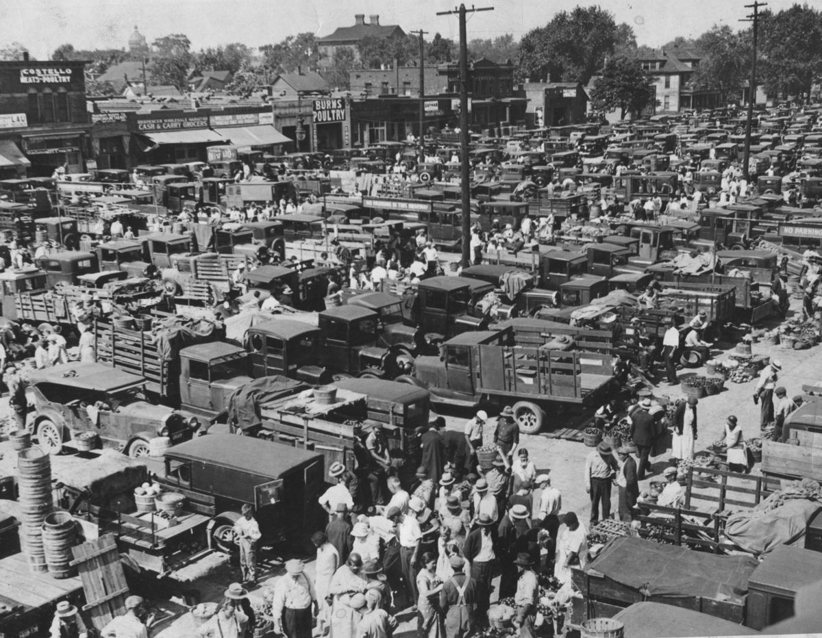 Historic Western Market in Detroit crowded with trucks, shoppers, and produce vendors.